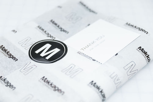 A product wrapped in tissue paper with the makkagen bag company logo and a thank you card