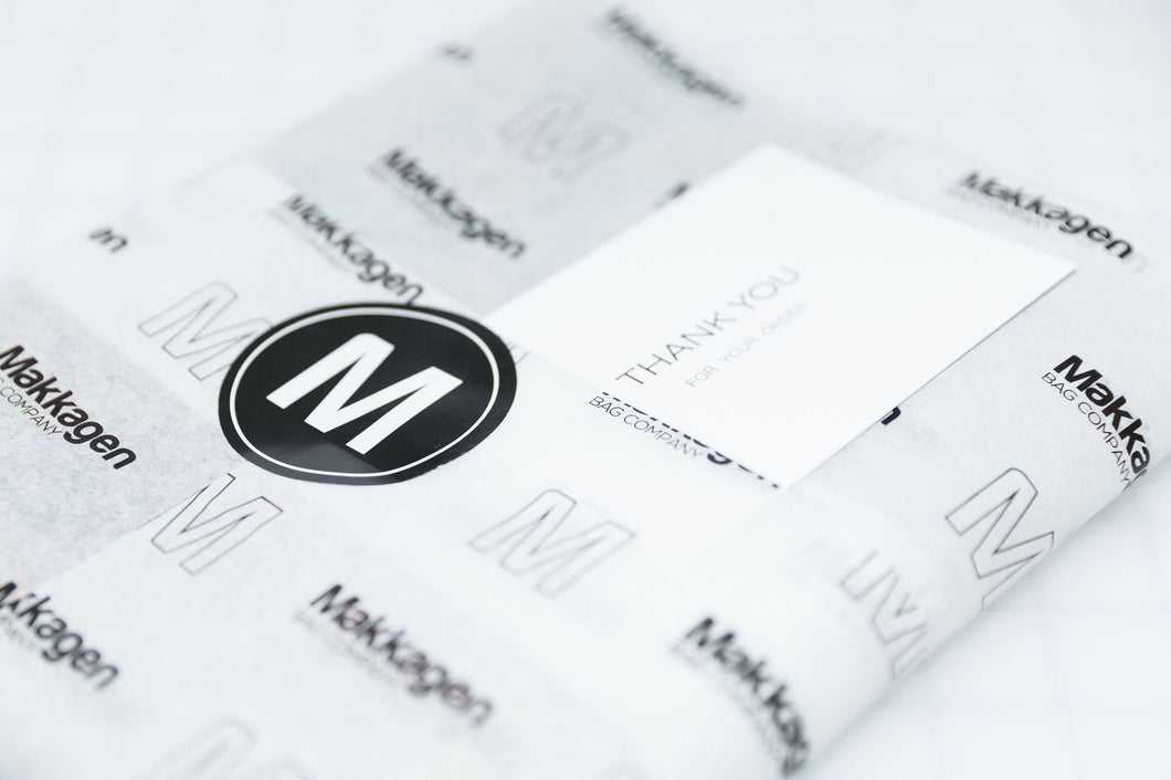 A product wrapped in tissue paper with the makkagen bag company logo and a thank you card